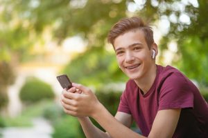 Young teen boy sitting outside and smiling while on phone. Anxiety isn't fun especially with all of the other life stresses teens deal with. Counseling for anxious teens in illinois is a great place to deal with OCD, perfectionism, anxiety, and confidence. Begin counseling for anxiety with Briefly Counseling today and start grasping hold of your life better.