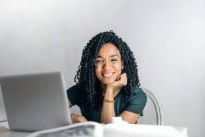 Photo of smiling African American teen on her computer representing how great she feels after having online anxiety treatment for teens in Illinois. 