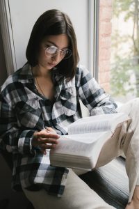 Teen in window reading bible. Learn how online Christian counseling for teens can help them feel more secure in their faith. Speak with a christian therapist in illinois who can help with faith and anxiety symptoms via solution focused brief therapy in Chicago, IL, Rockford, IL, and Champaign. 