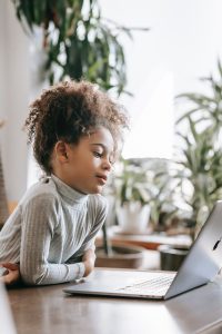 Young black girl sitting at laptop. Ready to get your child help with online therapy for kids? Learn how a solution focused therapist can help you worried kids overcome anxiety and phobias today! Begin counseling for anxious kids and start seeing an improvement in anxiety in kids!