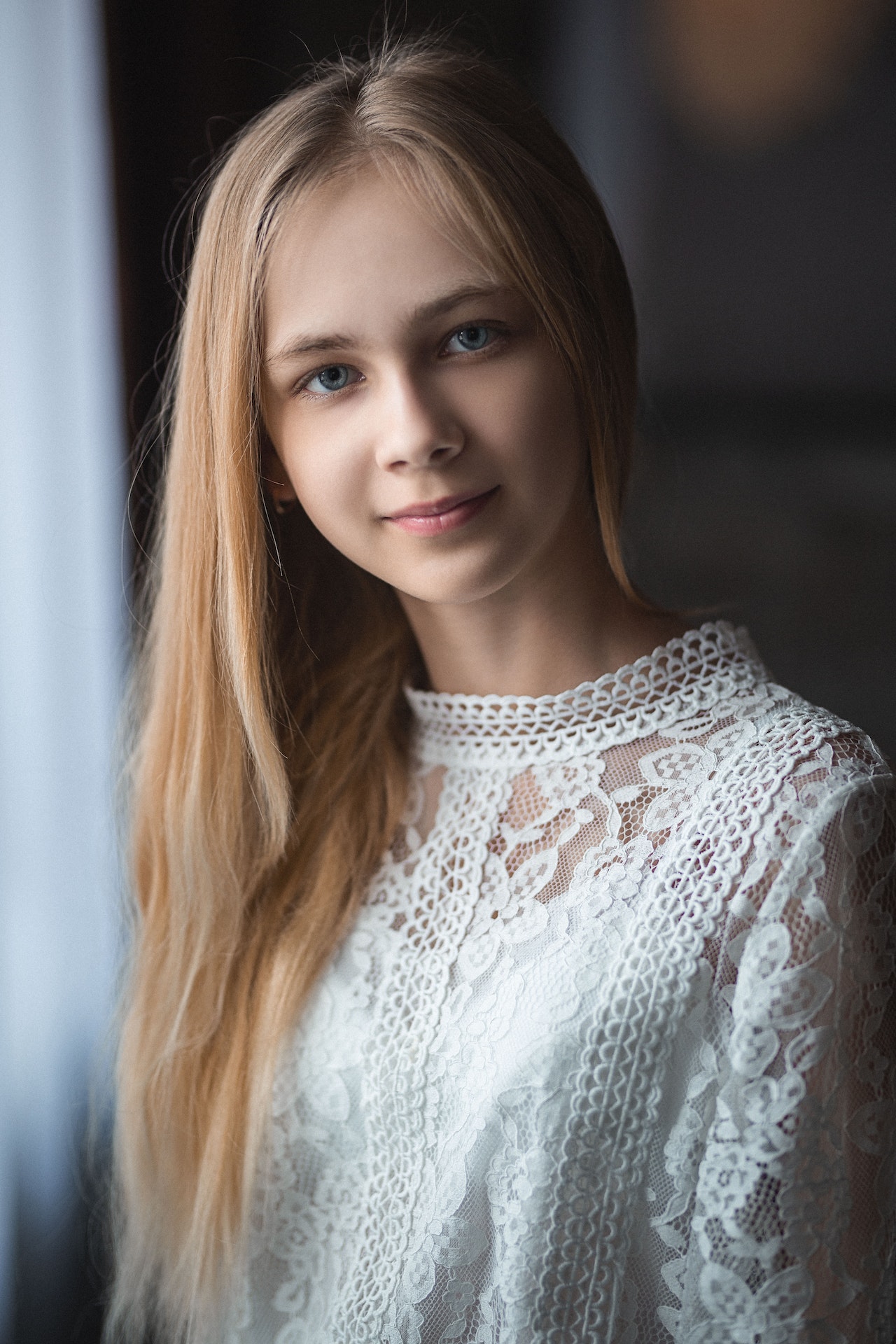 Photo of Caucasian teen girl with blond hair smiling slightly and wearing a lace blouse. Photo could represent the happiness she feels over having less anxiety due to online solution focused brief therapy in Illinois or Florida.