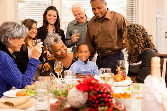 Photo of several people of different races sitting at a thanksgiving dinner table smiling at the African American boy sitting on his grandmother's lap. Photo could represent how much better this boy feels after receiving Christian counseling for his social anxiety from his Christian counselor in Illinois and Florida.